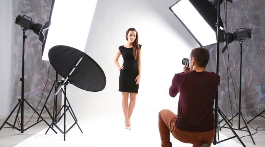 Female Model in a white dress getting photographed with Lighting and white backdrop